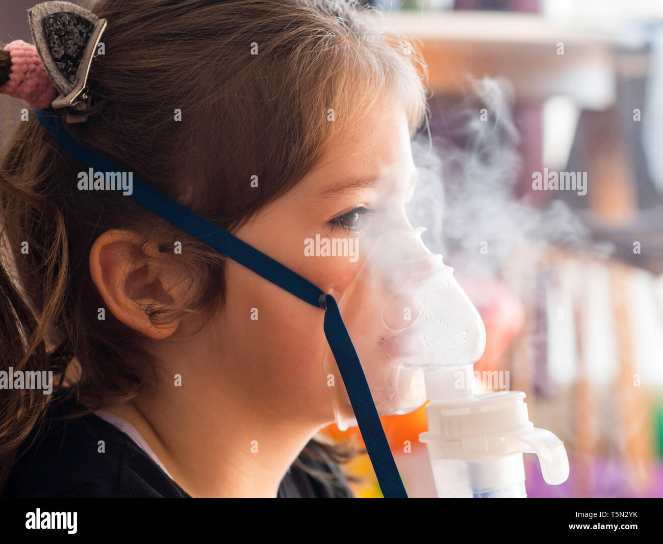 Cute caucasian girl with oxygen mask making inhalation Stock Photo