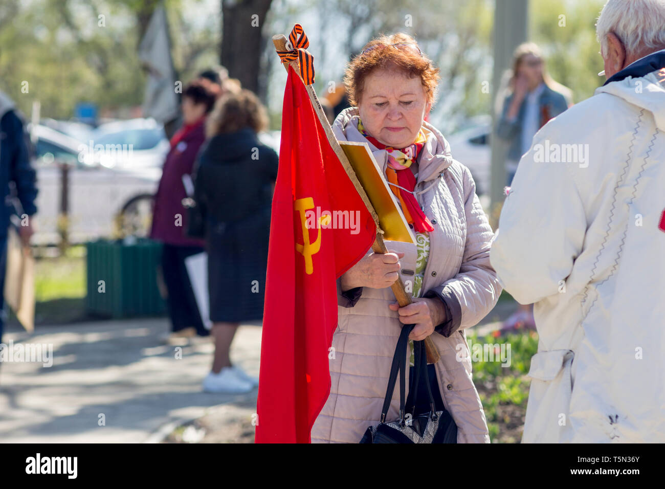 Russia, Nakhodka, 05/09/2017. Old woman holds Soviet Union's red flag. Annual Victory Day on May 9. Holiday in honor of victory of USSR over Nazi Germ Stock Photo