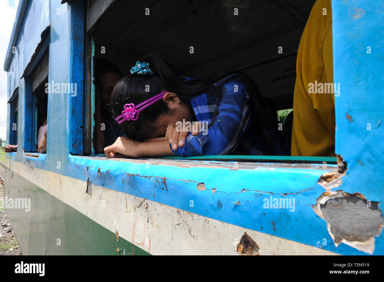 02.09.2013, Yangon, Republic of the Union of Myanmar, Asia - A girl is resting next to an open window inside a train compartment of the Circle Line. Stock Photo