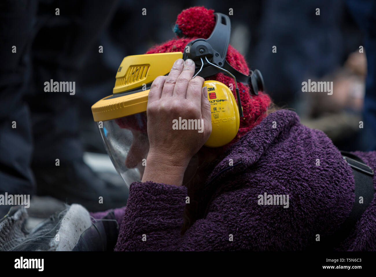 An environmental protester wears a protective helmet issued by police before a grinder is used to saw through chains on the road in Fleet Street on the 11th and final day of protests, road-blockages and arrests across London by the climate change campaign Extinction Rebellion, on 25th April 2019, in London, England. Stock Photo