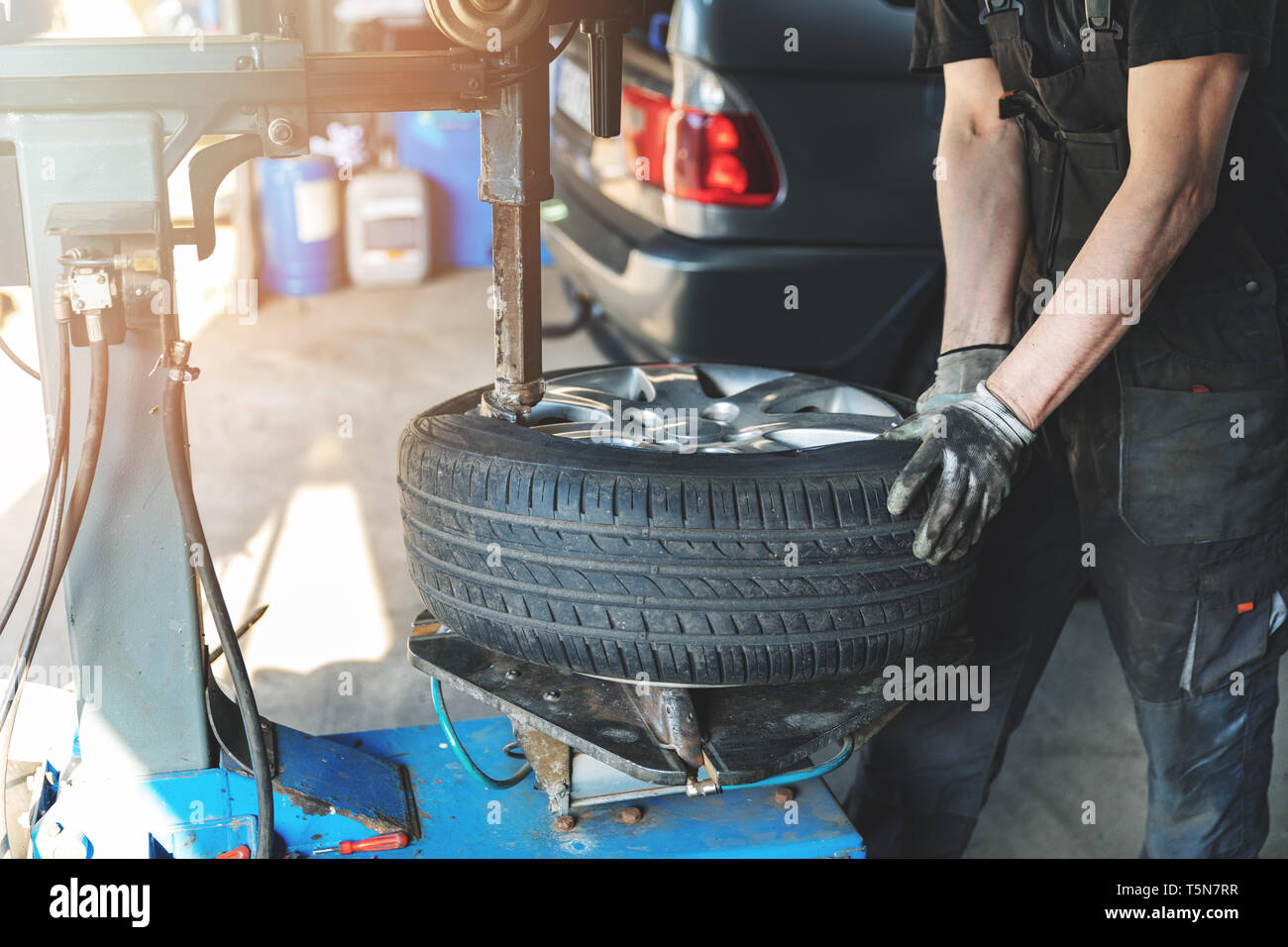 car mechanic changing tire on the rim in service garage Stock Photo