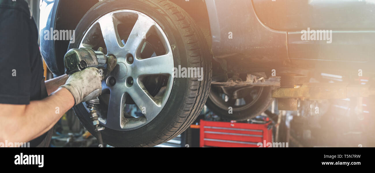 car mechanic screwing the wheel at auto repair garage Stock Photo