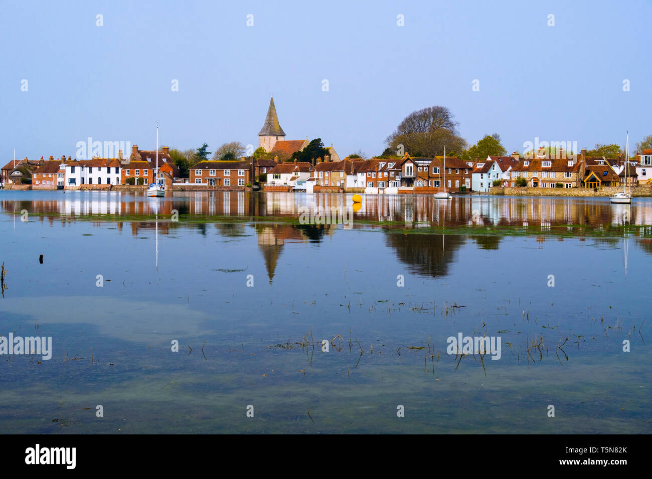 Old village houses and church reflected in still waters of Bosham Creek at high tide in Chichester harbour. Bosham, West Sussex, England, UK, Britain Stock Photo