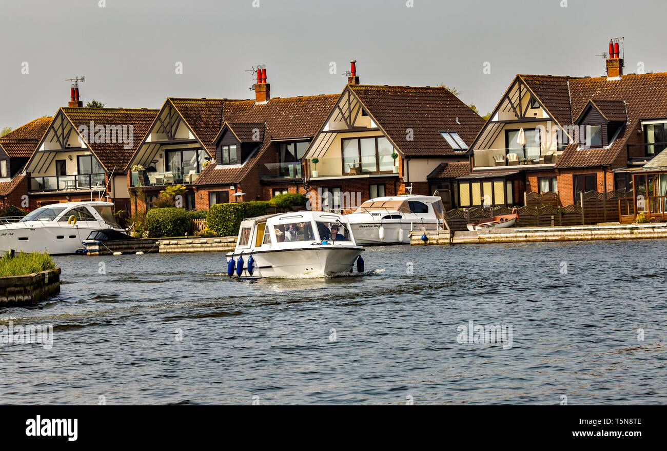 Small hire boat navigating the River Bure in Horning, a village in the heart of the Norfolk
