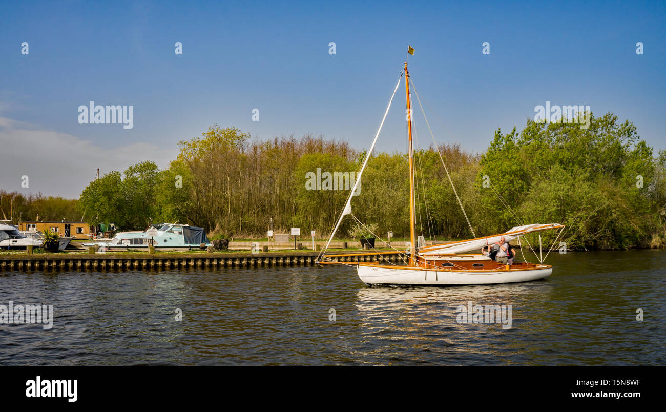 A traditional wooden Norfolk Broads cruiser navigating the River Bure in Horning. Originally these boats would not have an engine and would use just t Stock Photo