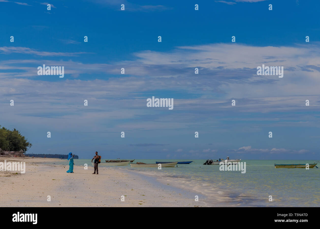 Zanzibar, Tanzania, march 21, 2018. Boy and girl are chatting in the distance while standing on the beach in national Muslim clothes standing near the Stock Photo