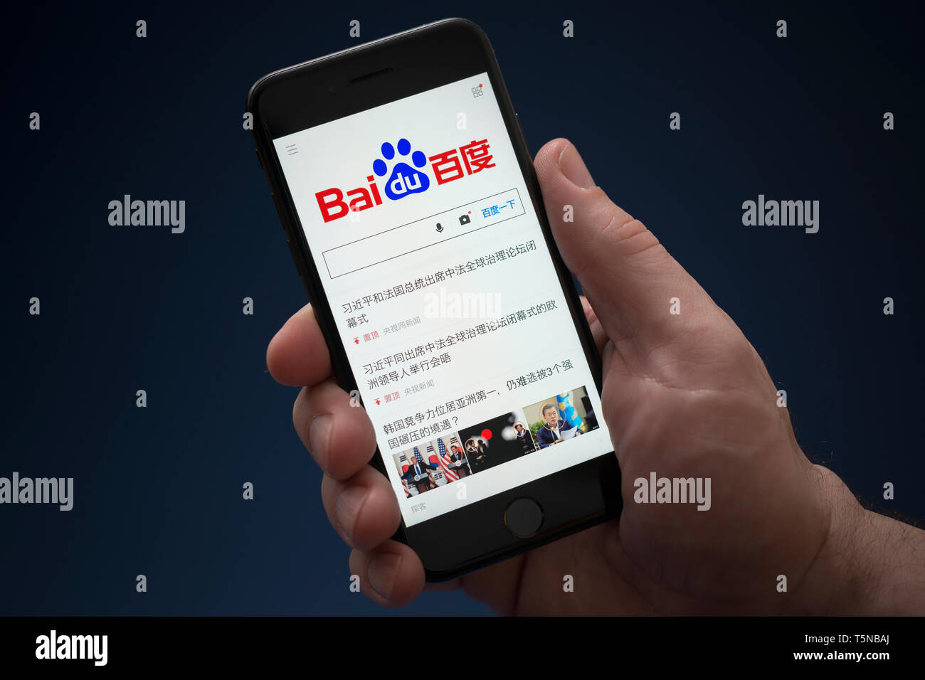 A man looks at his iPhone which displays the Baidu logo (Editorial use only). Stock Photo