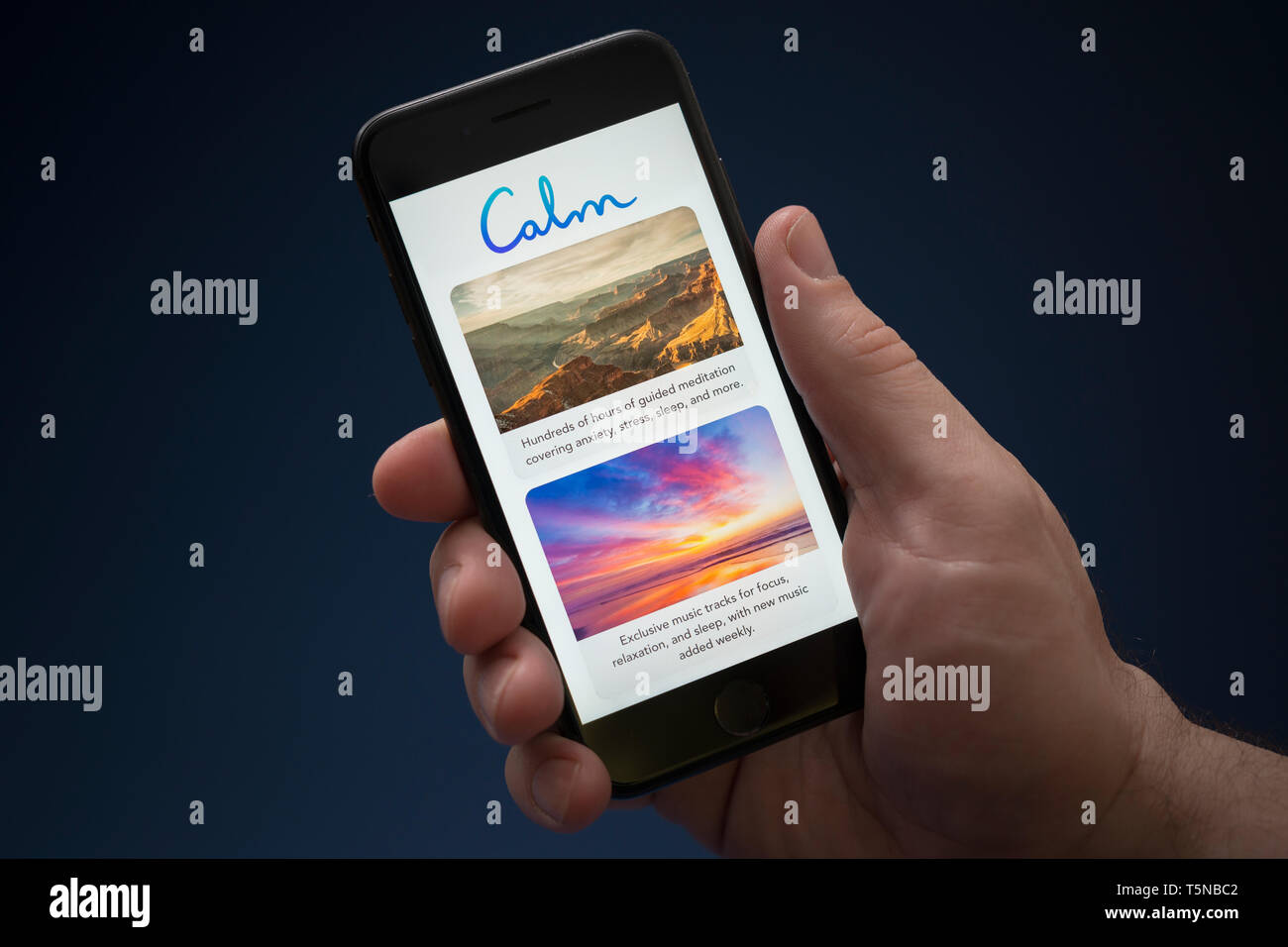 A man looks at his iPhone which displays the Calm logo (Editorial use only). Stock Photo