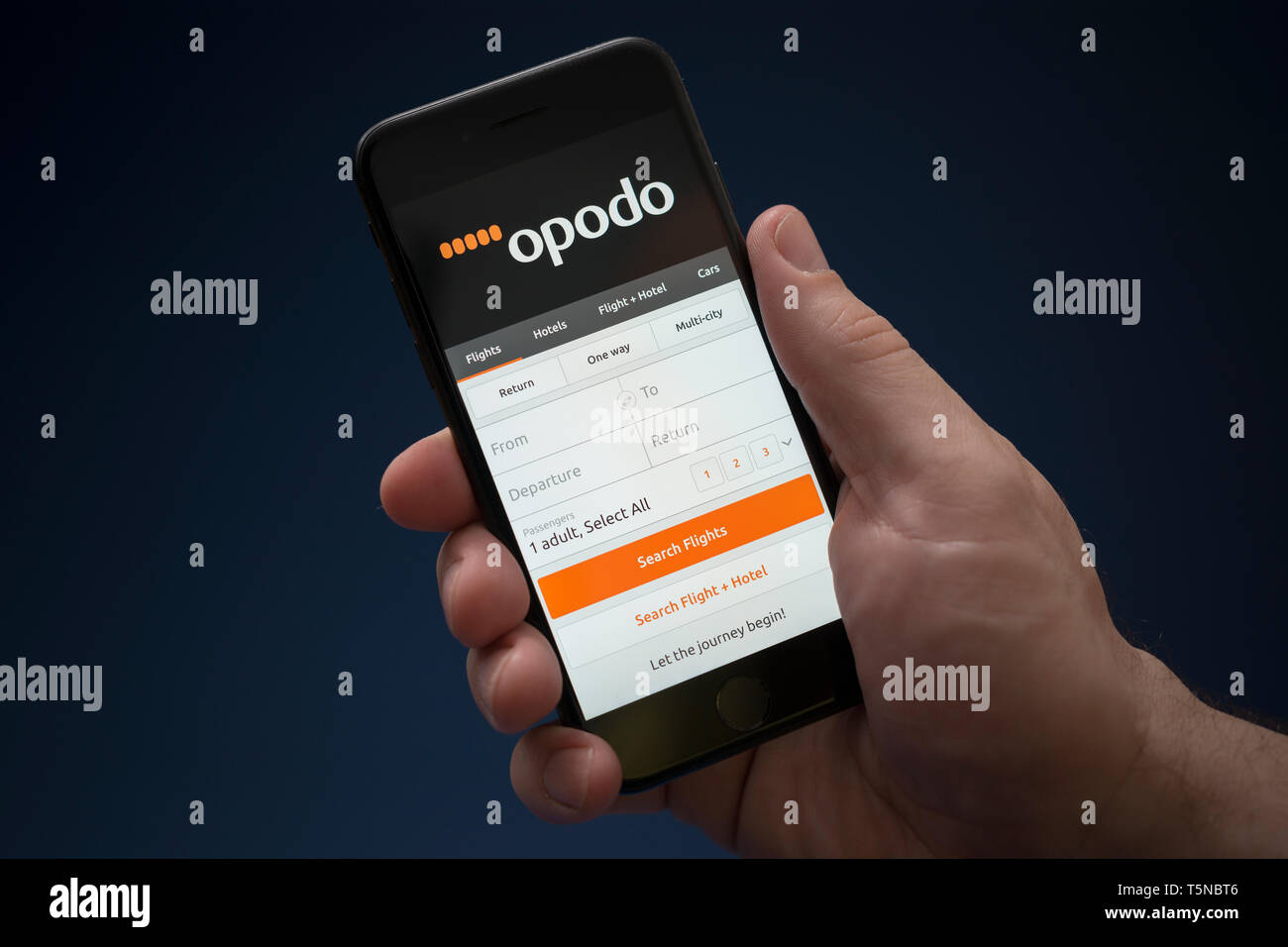 A man looks at his iPhone which displays the Opodo logo (Editorial use only). Stock Photo