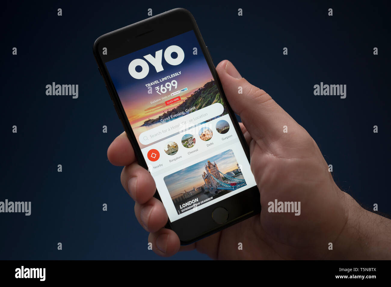 A man looks at his iPhone which displays the Oyo Rooms logo (Editorial use only). Stock Photo