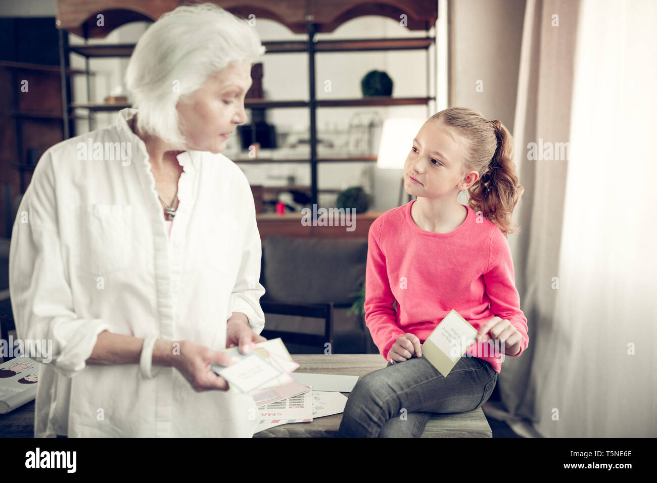 Girl answering the question on flashcard while playing with granny Stock Photo