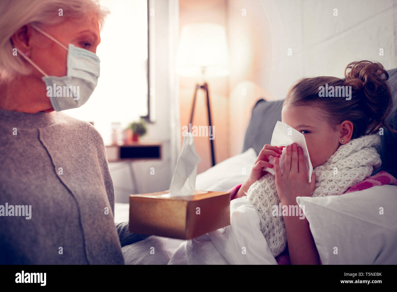 Granny giving granddaughter with running nose some napkins Stock Photo