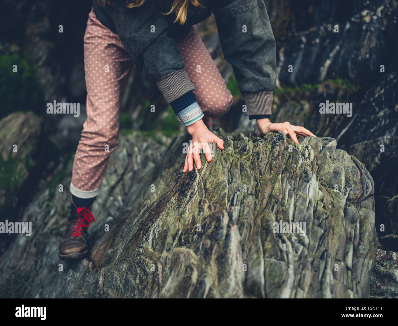 A young woman is climbing a rock on the beach Stock Photo