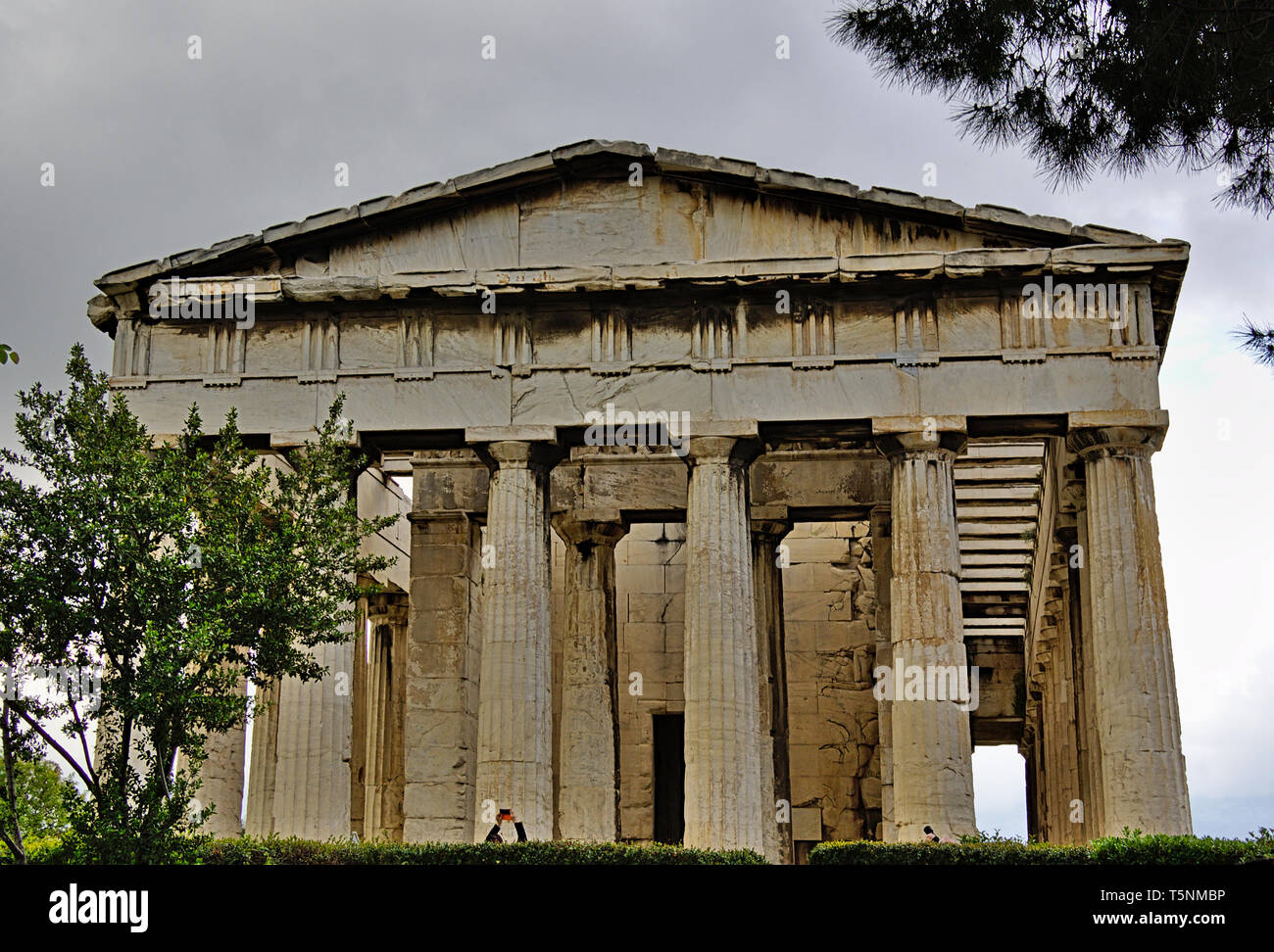 Temple of Hephaestus in Athens, Greece. Tourists taking photos. Cloudy sky and trees. Stock Photo