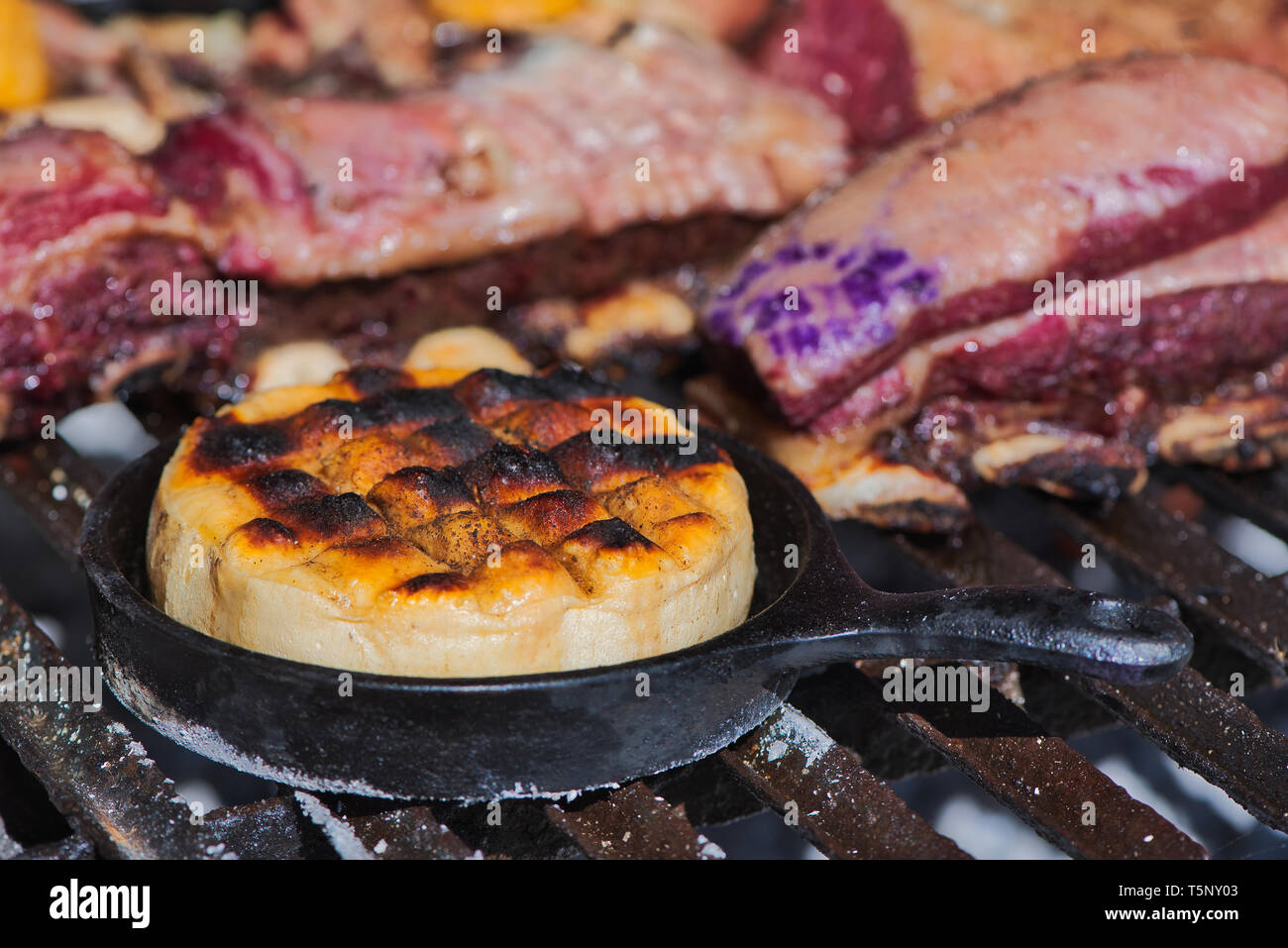 Delicious Argentinian Provolone Yarn Cheese (Provoleta) that is cooked in a cast iron skillet over the grill of a barbecue, Buenos Aires, Argentina Stock Photo