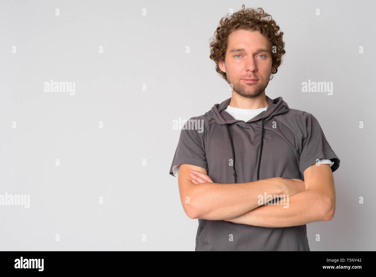 Portrait of handsome man with curly hair crossing arms Stock Photo - Alamy