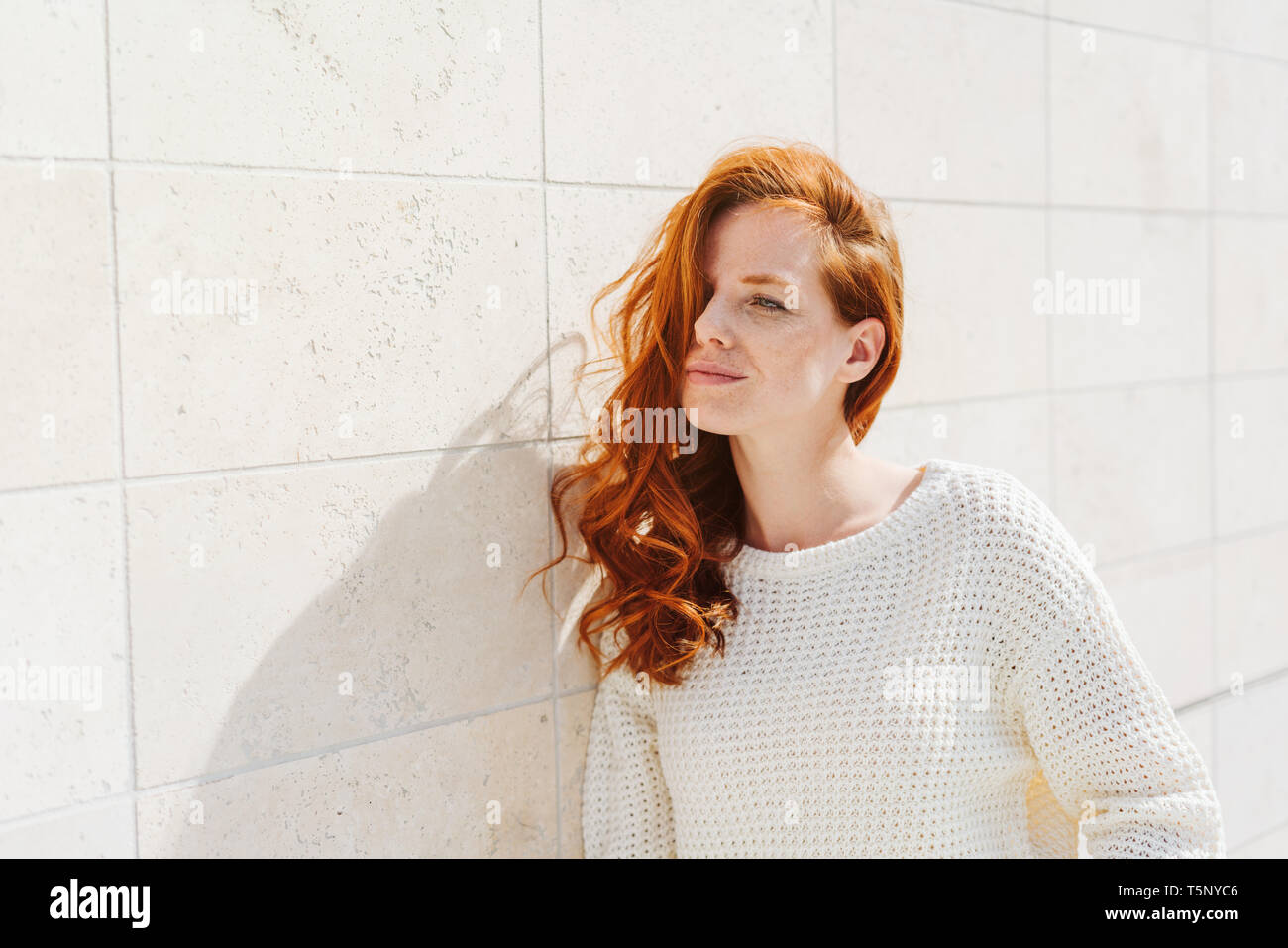 Young Red Haired Woman With Long Curly Hair Wearing White Sweater