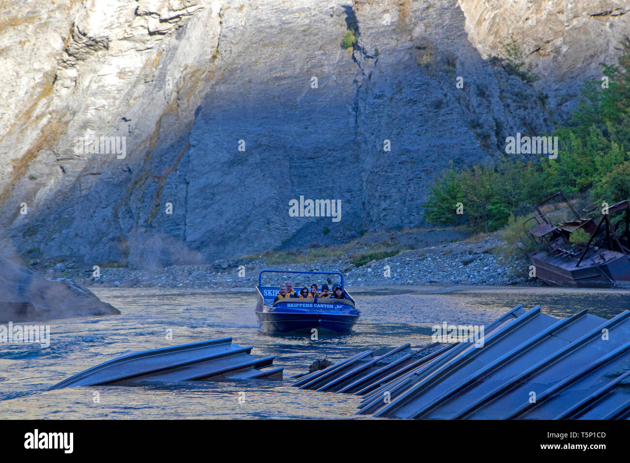 Jet boat passing gold mining relics in Skippers Canyon Stock Photo