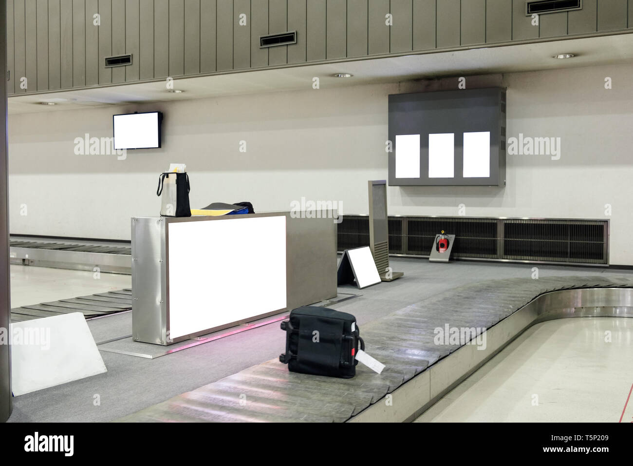 Luggage sliding on conveyor in airport with billboard Stock Photo