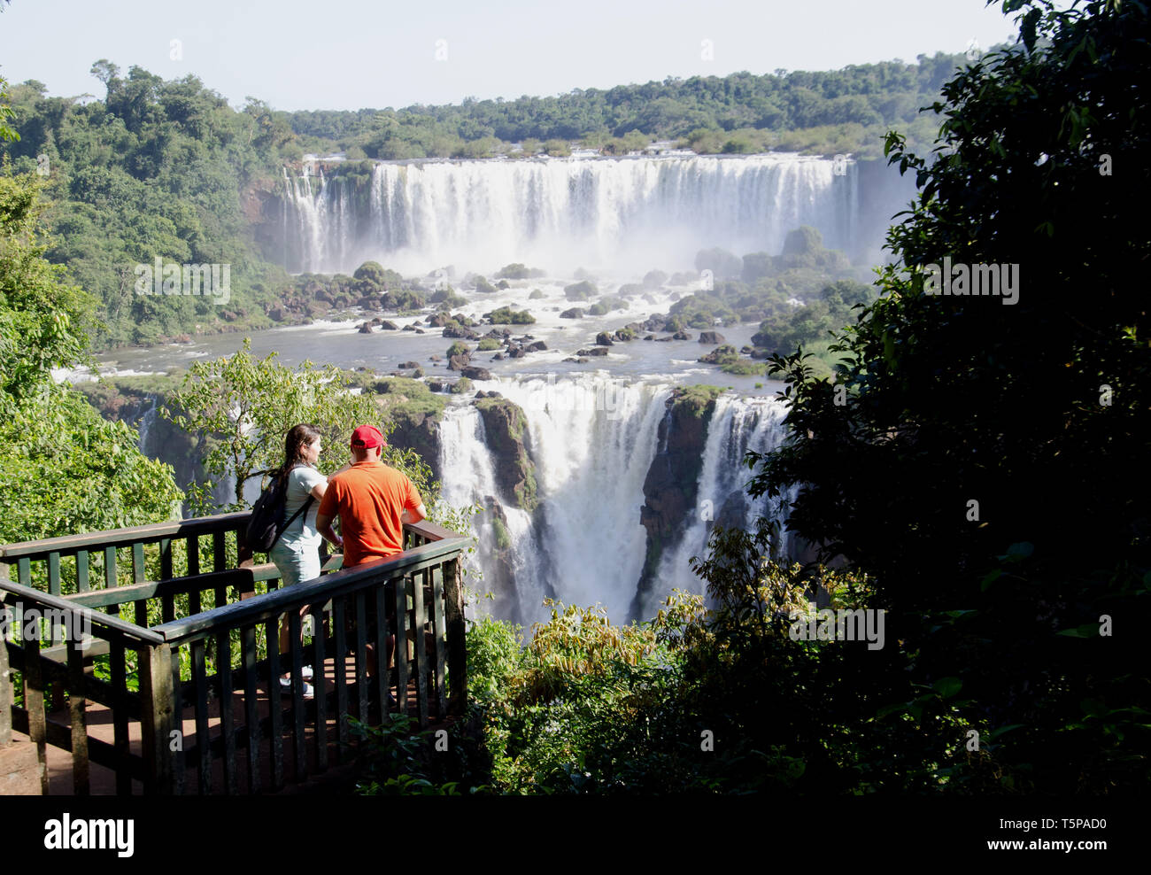 A tourist couple share a spectacular view of the mighty Iguaçu falls from the Brazil side Stock Photo