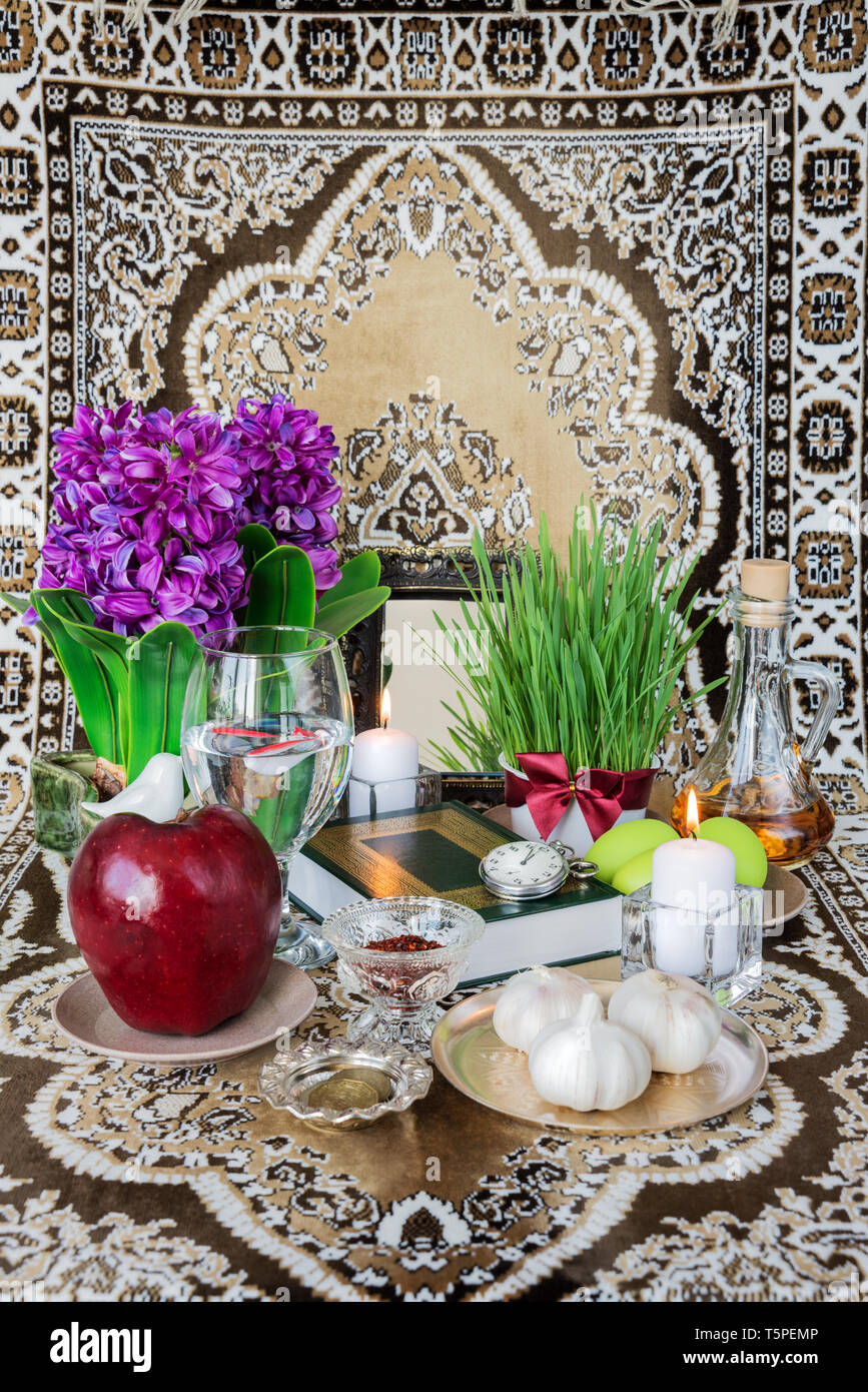 Tabletop with Haft-seen elements for Nowruz: sonbol (hyacinth), sabzeh (grass), seeb (apple), somaq (sumac powder), seer (garlic), serkeh (vinegar), g Stock Photo