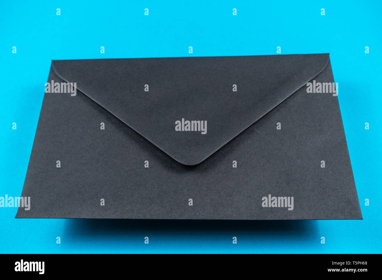 Black closed envelope on light blue background Stock Photo - Alamy