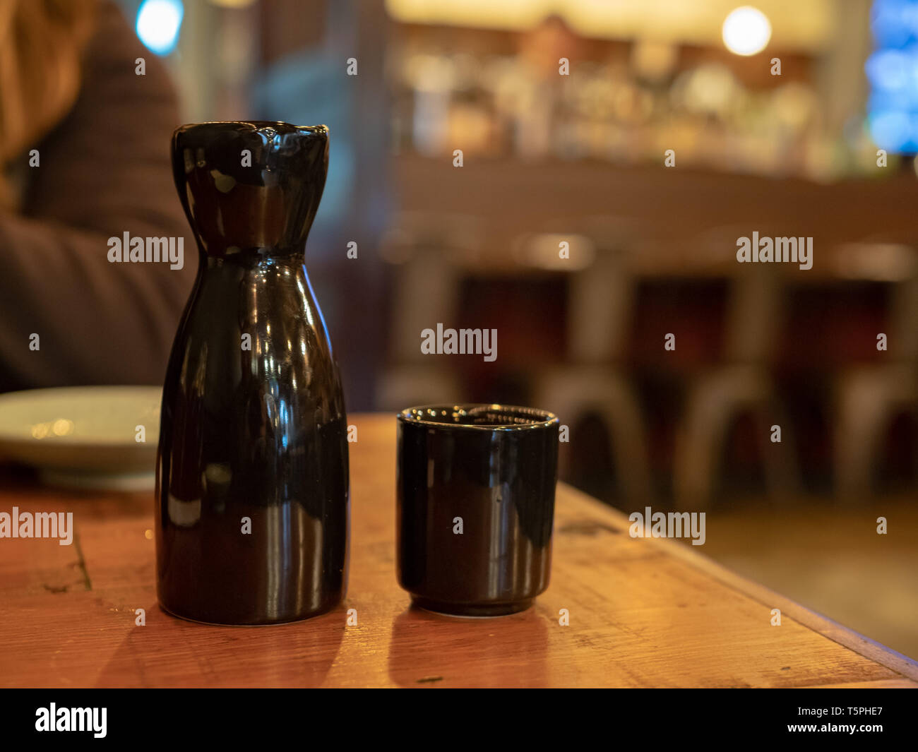 Black sake bottle and glass sitting on table at dining area Stock Photo