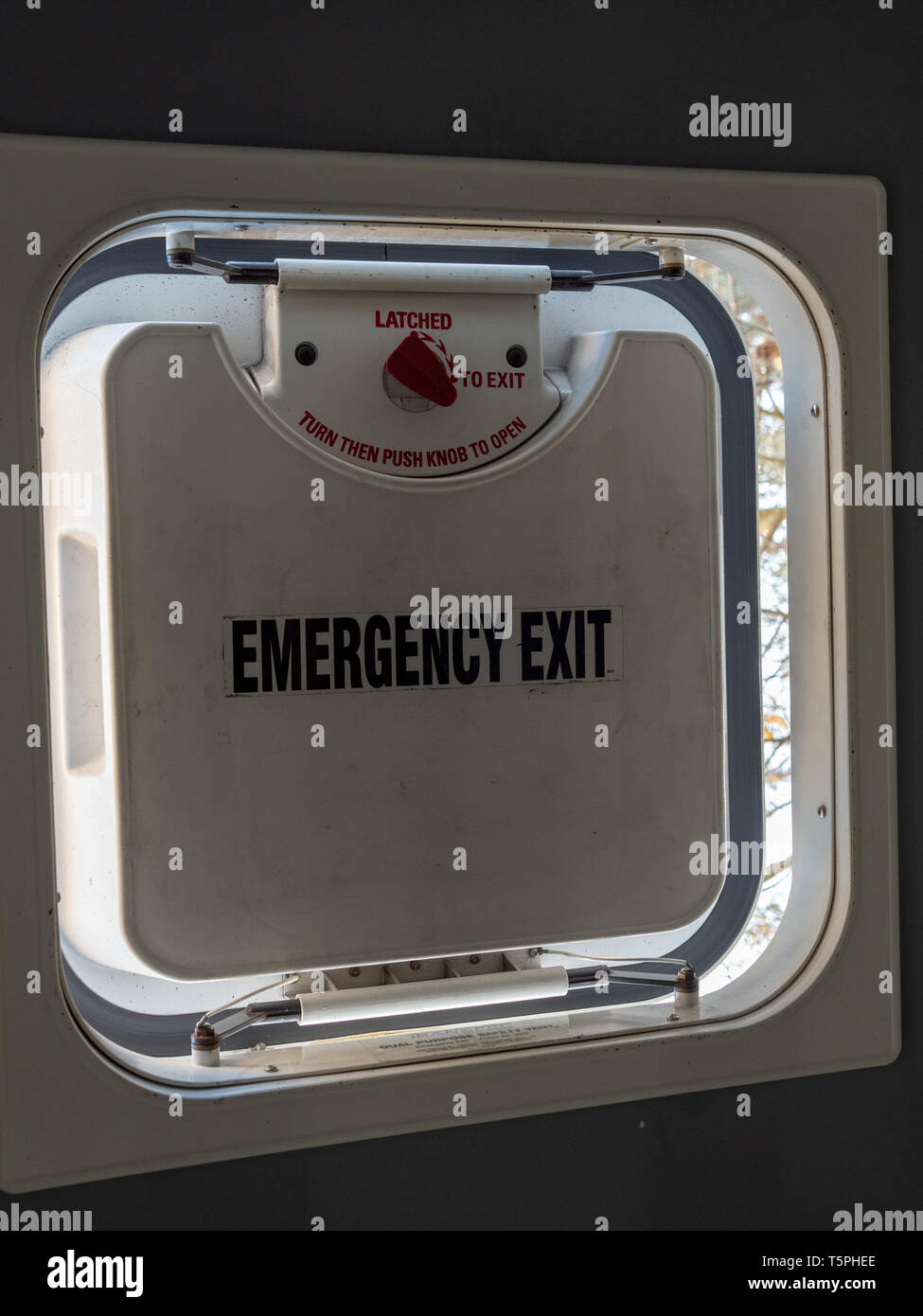 Emergency exit hatch partially open in a bus with latch and daytime Stock Photo