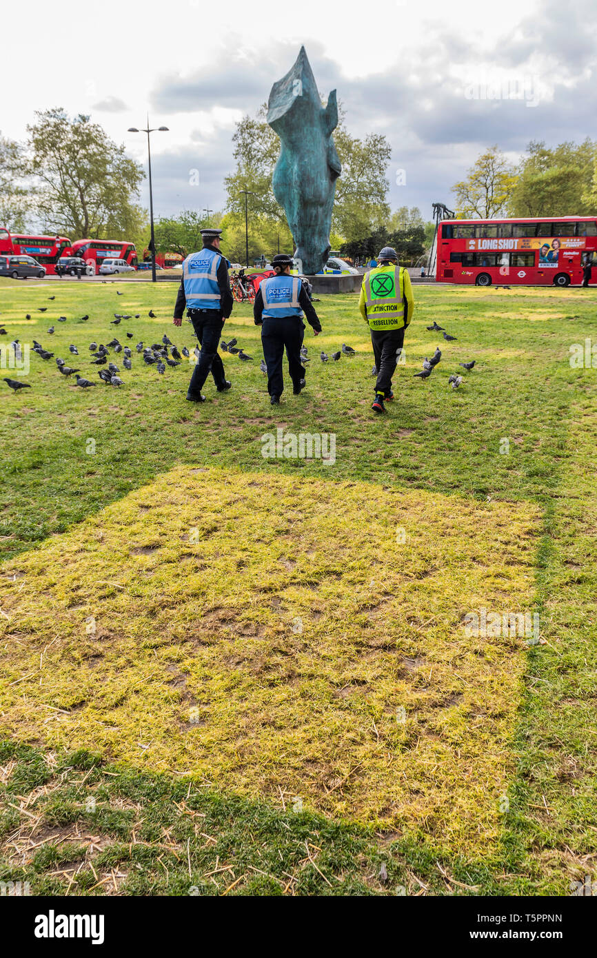 Marble Arch, London, UK. 26th Apr, 2019. Police and an ER rep head to talk to the last camper - A ghost town, marked only by yellow patches on the grass, with only one reamining camper. The site of the Extinction Rebellion Camp at Marble Arch. Credit: Guy Bell/Alamy Live News Stock Photo