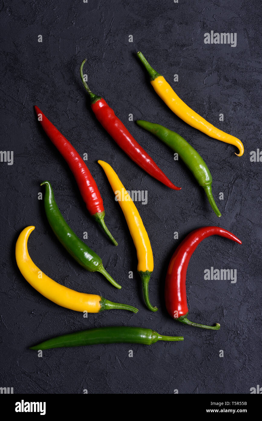 Assoted different colored chilli peppers on dark background Stock Photo