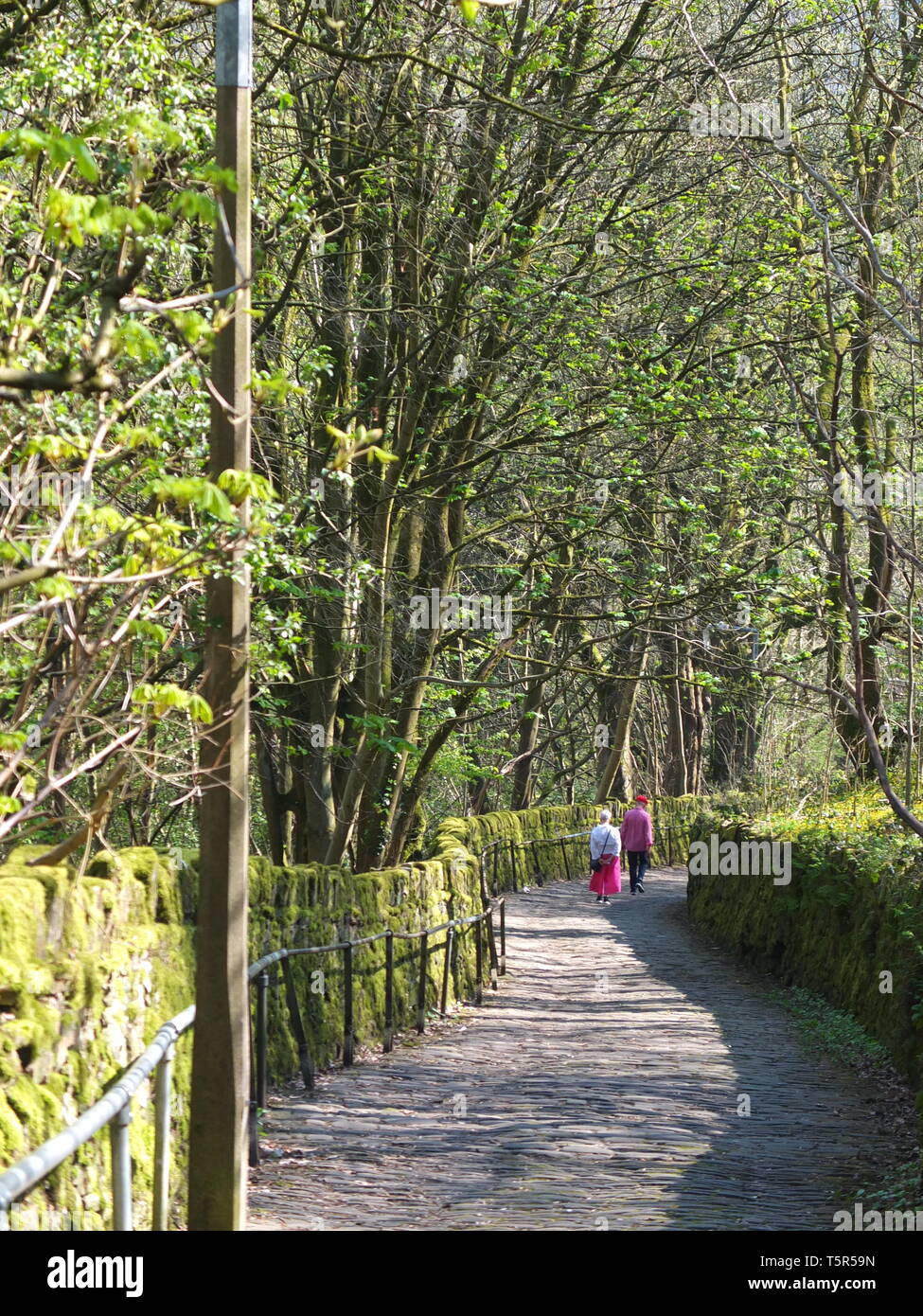 A couple in the distance walking up The Buttress, a steep cobbled path leading from the Calderdale town of Hebden Bridge to the Heptonstall Stock Photo