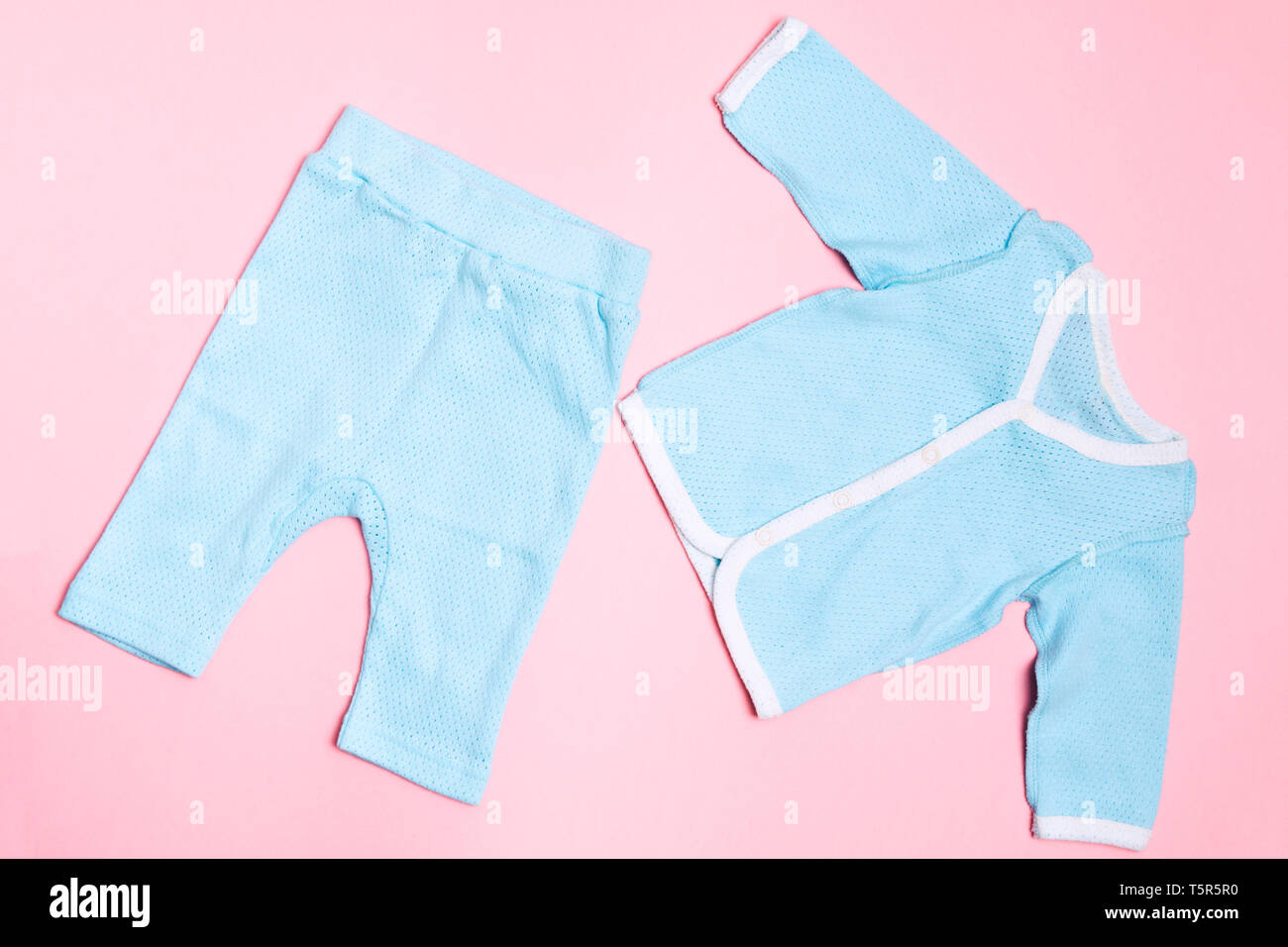 Blue baby clothes on pink background with shirt and trousers. Child design summer fashion. Flat lay. Top view Stock Photo