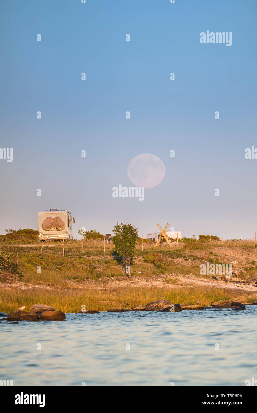 Camping in nature, camper van parked at a beach in a beautiful landscape with full moon rising behind, Gotland, Sweden, Scandinavia Stock Photo