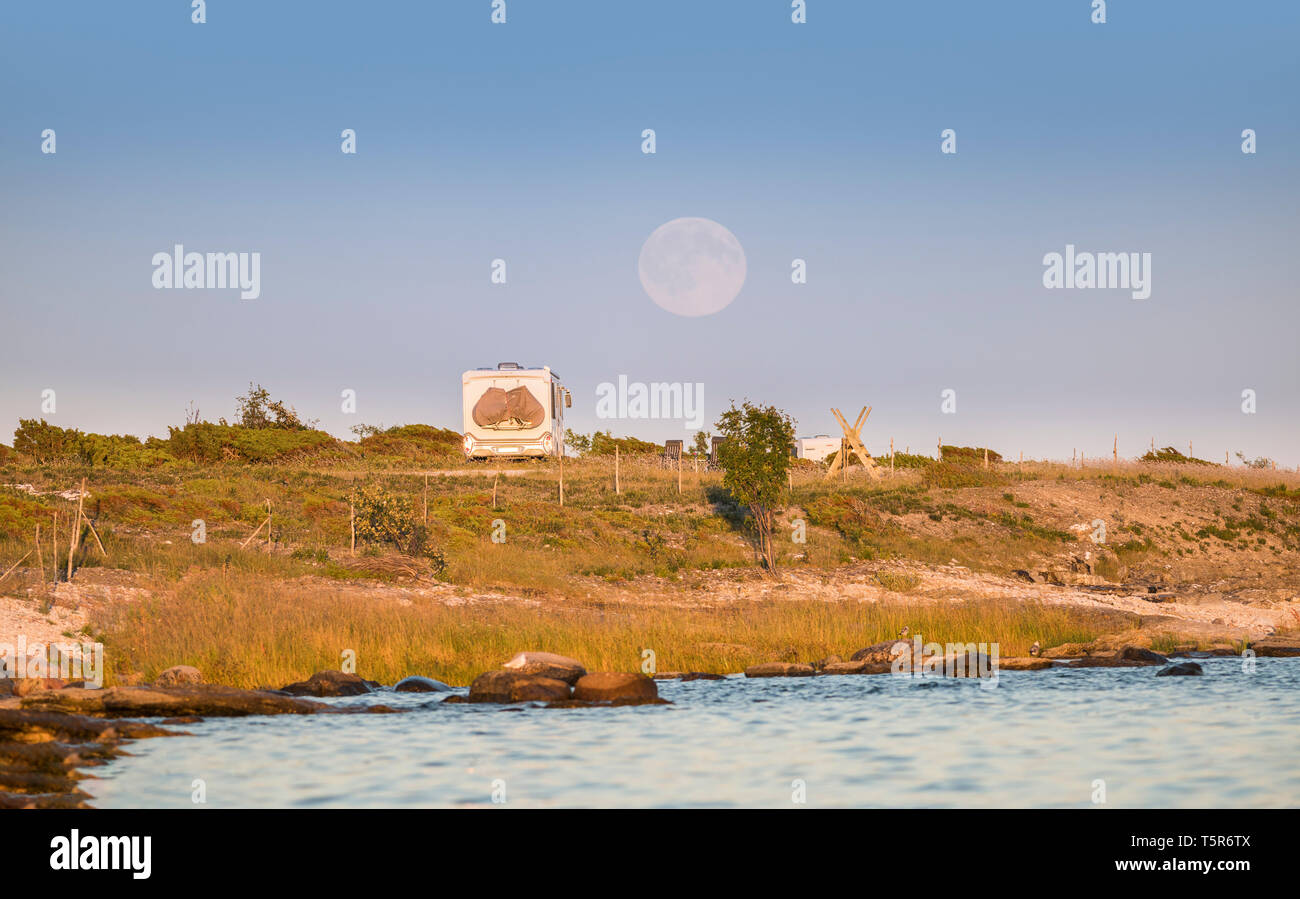 Camping in nature, camper van parked at a beach in a beautiful landscape with full moon rising behind, Gotland, Sweden, Scandinavia Stock Photo