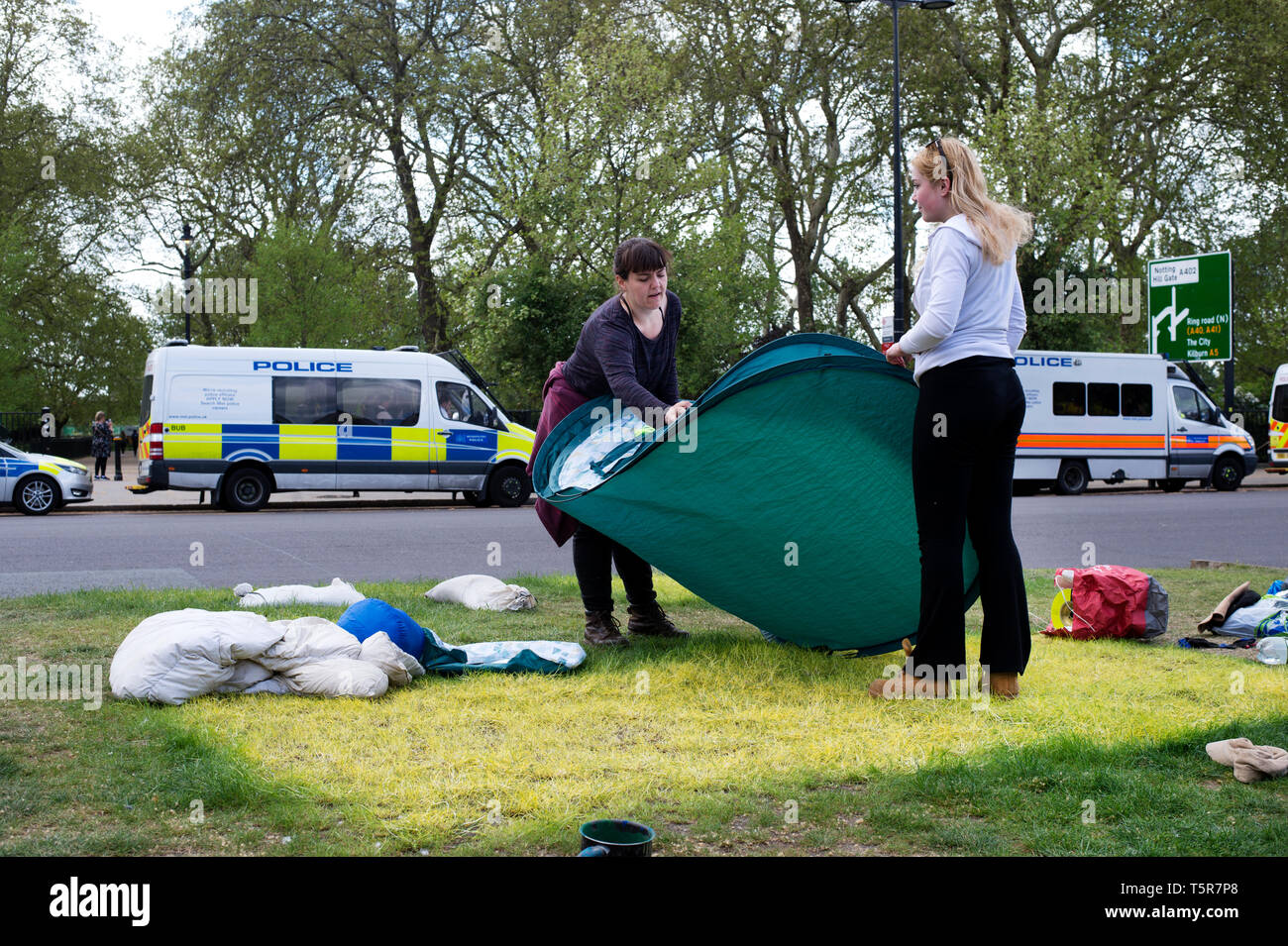 Extinction Rebellion protest, London . April 25th 2019. Marble Arch camp. Marks on the grass left by tents. Two women dismantle their tent. Stock Photo