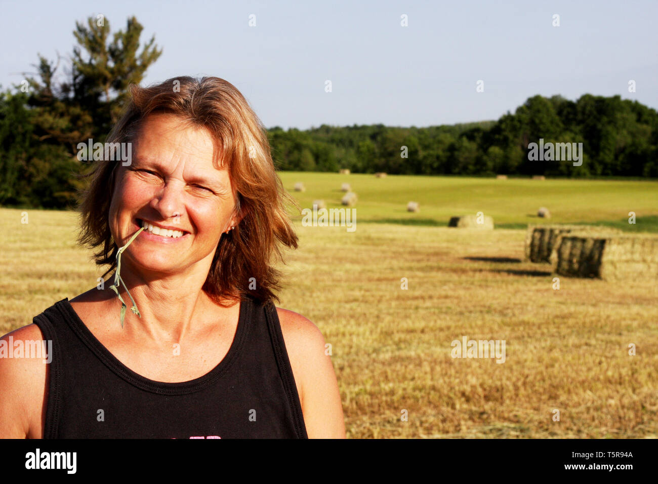 Woman farmer on a Hay Field with bales in the background Stock Photo