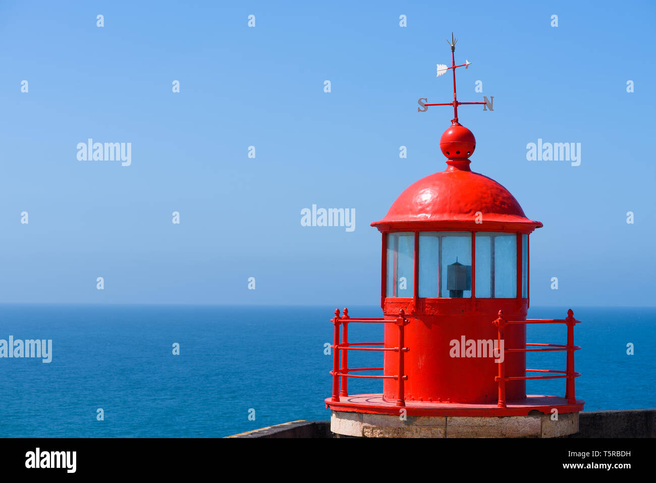 Red lighthouse roof cupola lantern room with a wind vane over clear