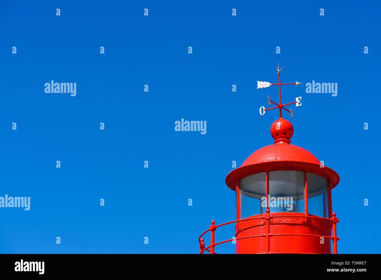 Red lighthouse roof cupola lantern room with a wind vane over clear blue summer sky background with copy space Stock Photo