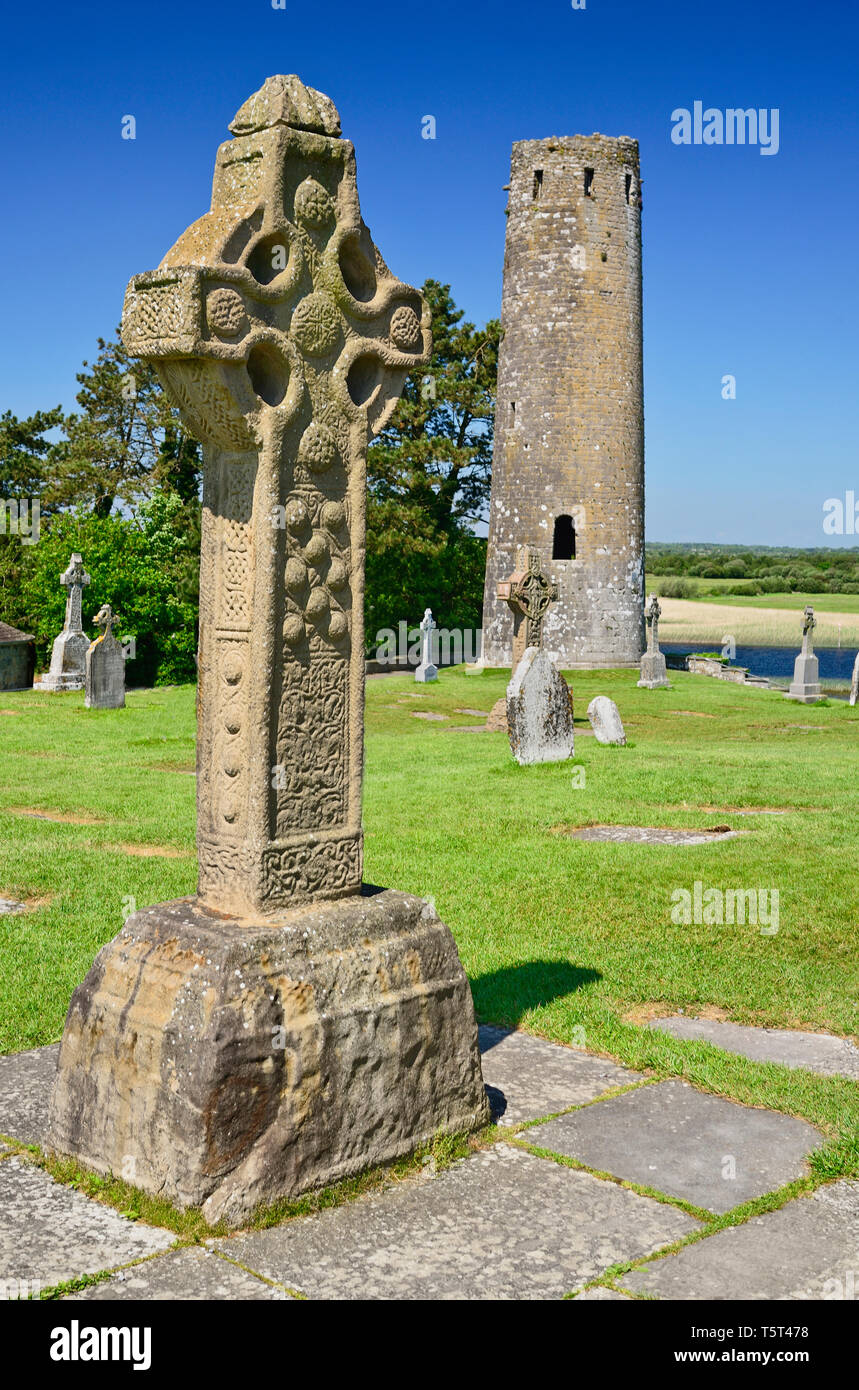 Ireland, County Offaly, Clonmacnoise Monastic Settlement, Replica of the South Cross with Round Tower in the background. Stock Photo