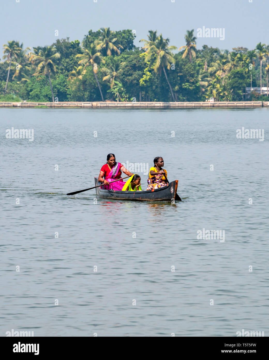 Vertical view of ladies paddling across a lagoon in a canoe in Alleppy