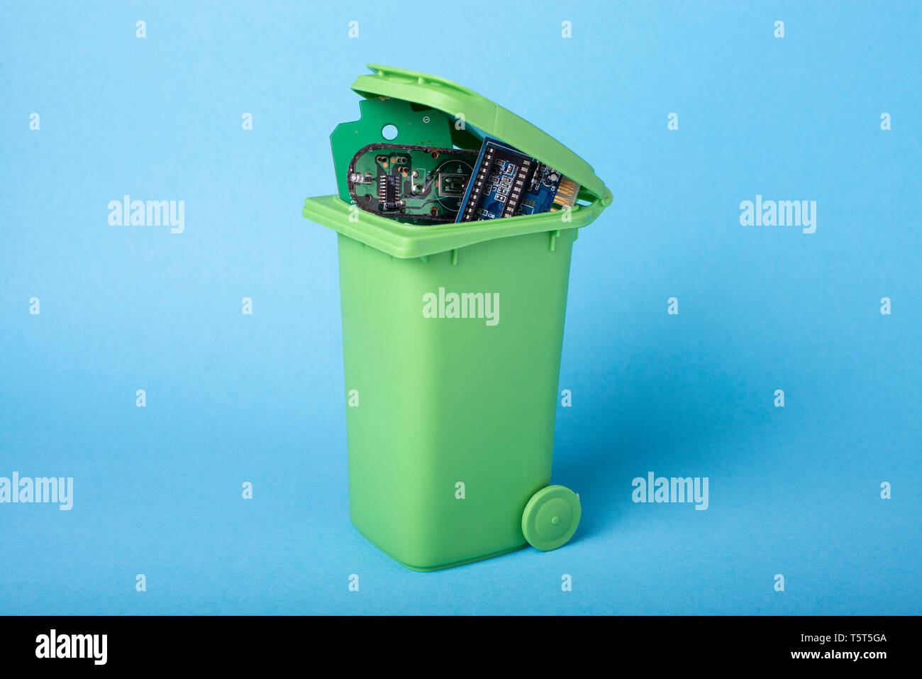 Electronic components in a green waste basket.Waste recycling