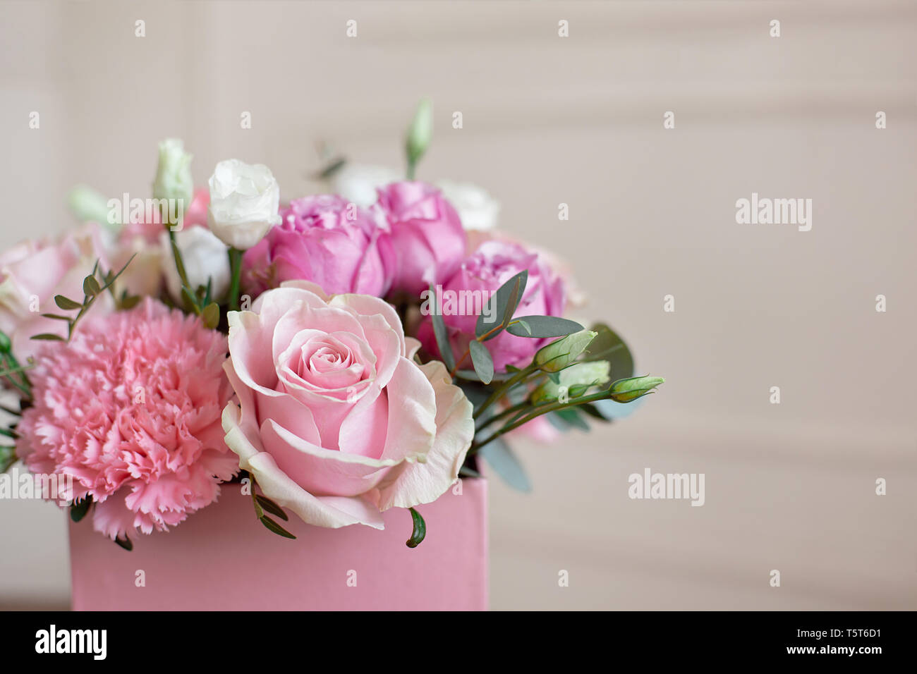 Stylish wedding bouquet bride of pink roses, white carnation and green flowers and greens with ribbons lying on pastel table Stock Photo