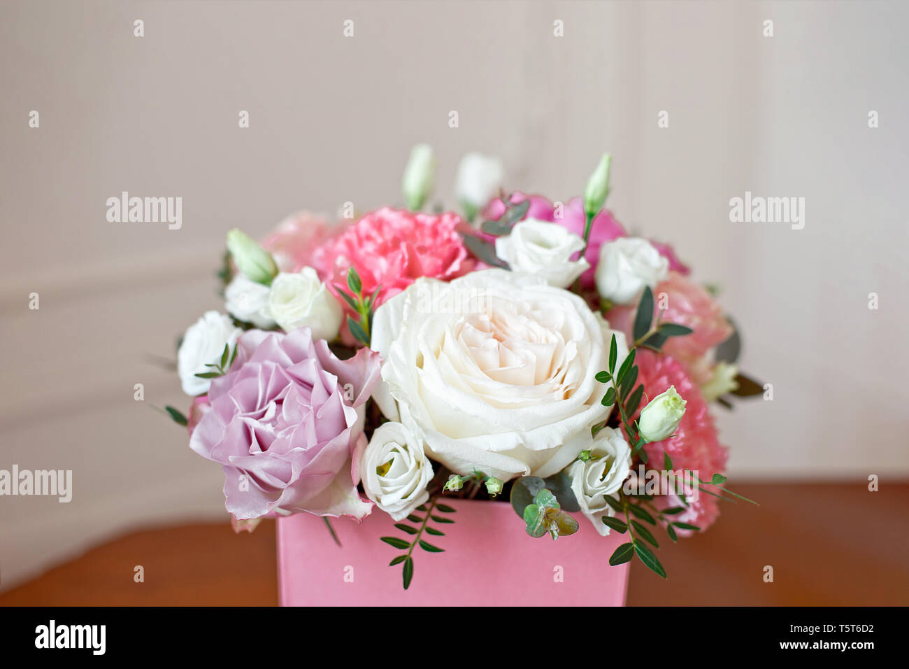 Stylish wedding bouquet bride of pink roses, white carnation and green flowers and greens with ribbons lying on pastel table Stock Photo