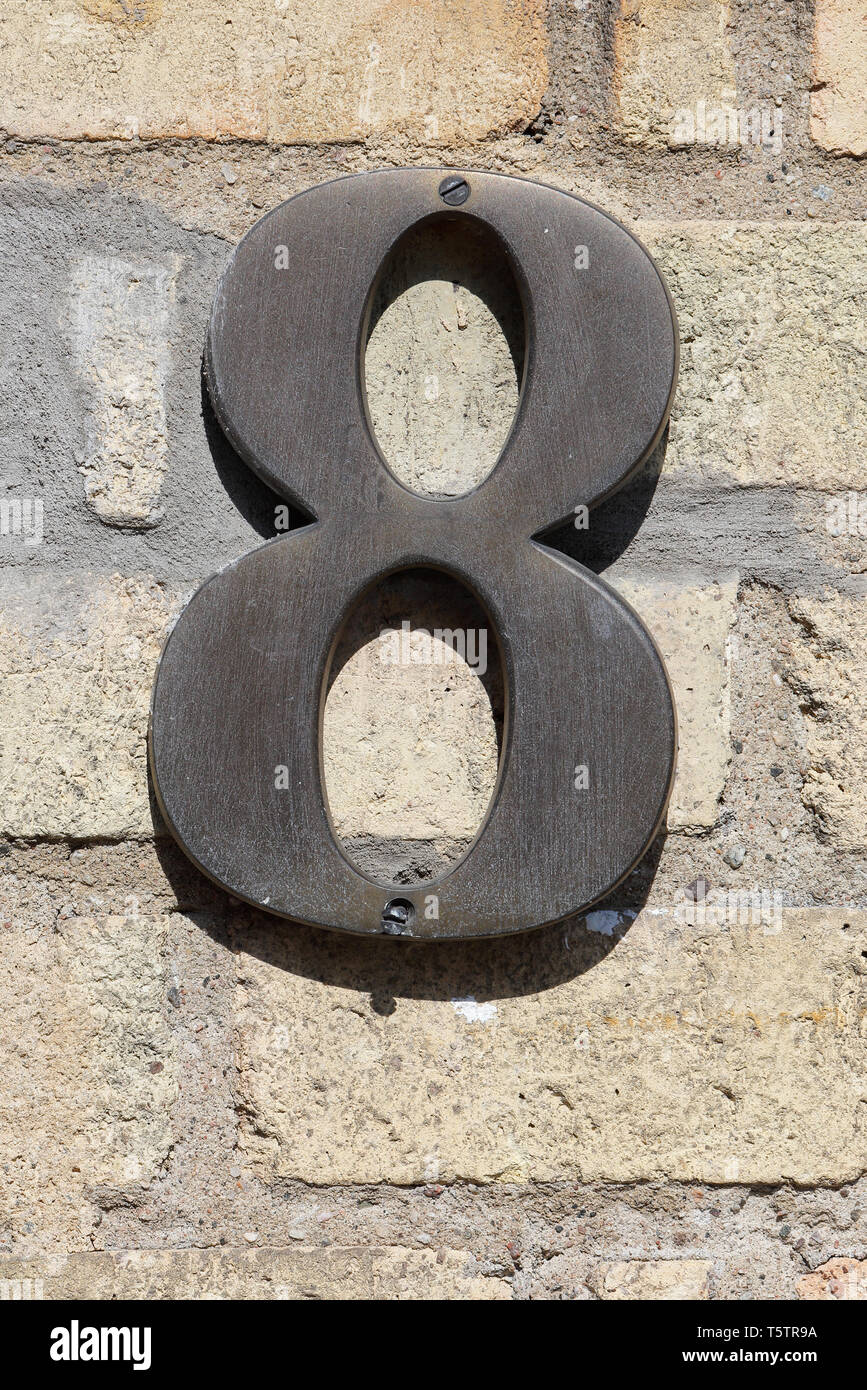 Number eight on a yellow brick wall. Stock Photo