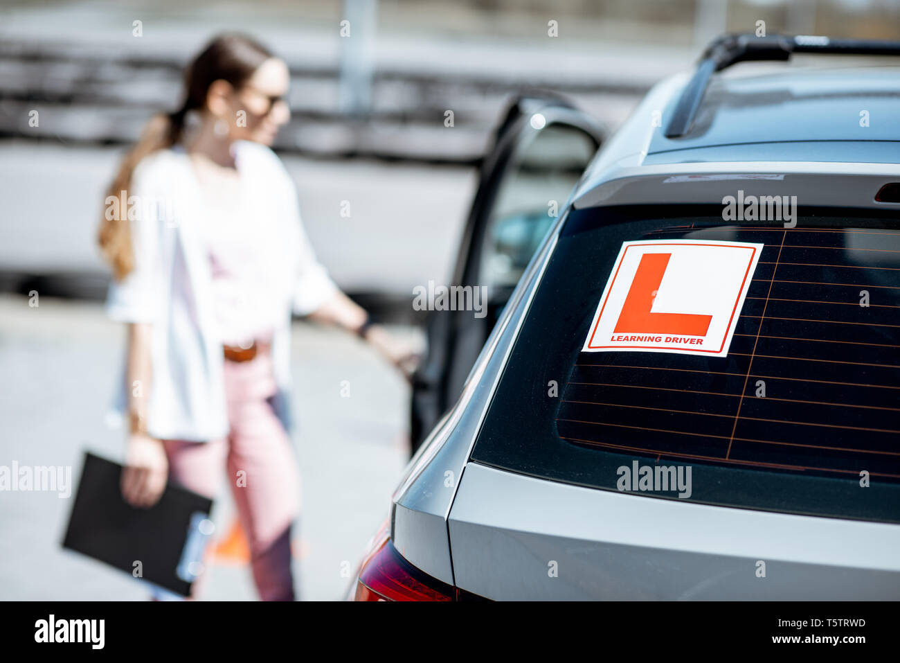 Learning sign on the car with woman driver on the background at the driving school outdoors Stock Photo