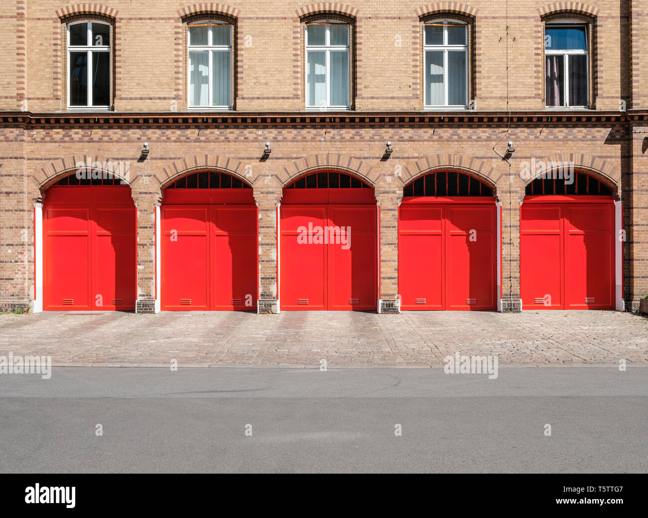 fire department builidng facade with red doors and empty street Stock Photo