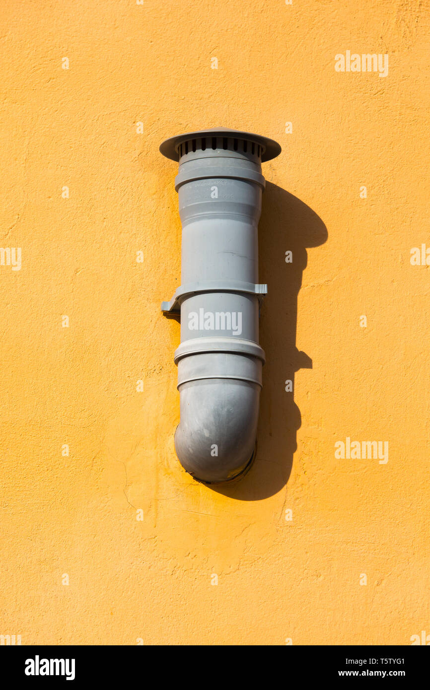 Plastic vent pipe on the orange wall. Air ventilation pipe mounted on