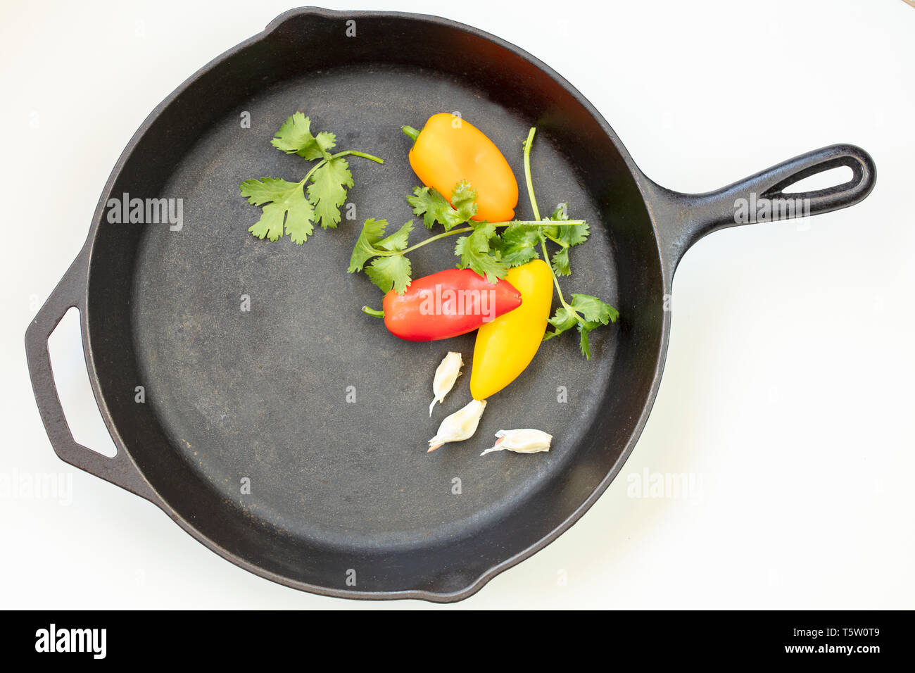Blasck Cast Iron Skillet with red, yellow and orange peppers, parsley and garlic Stock Photo