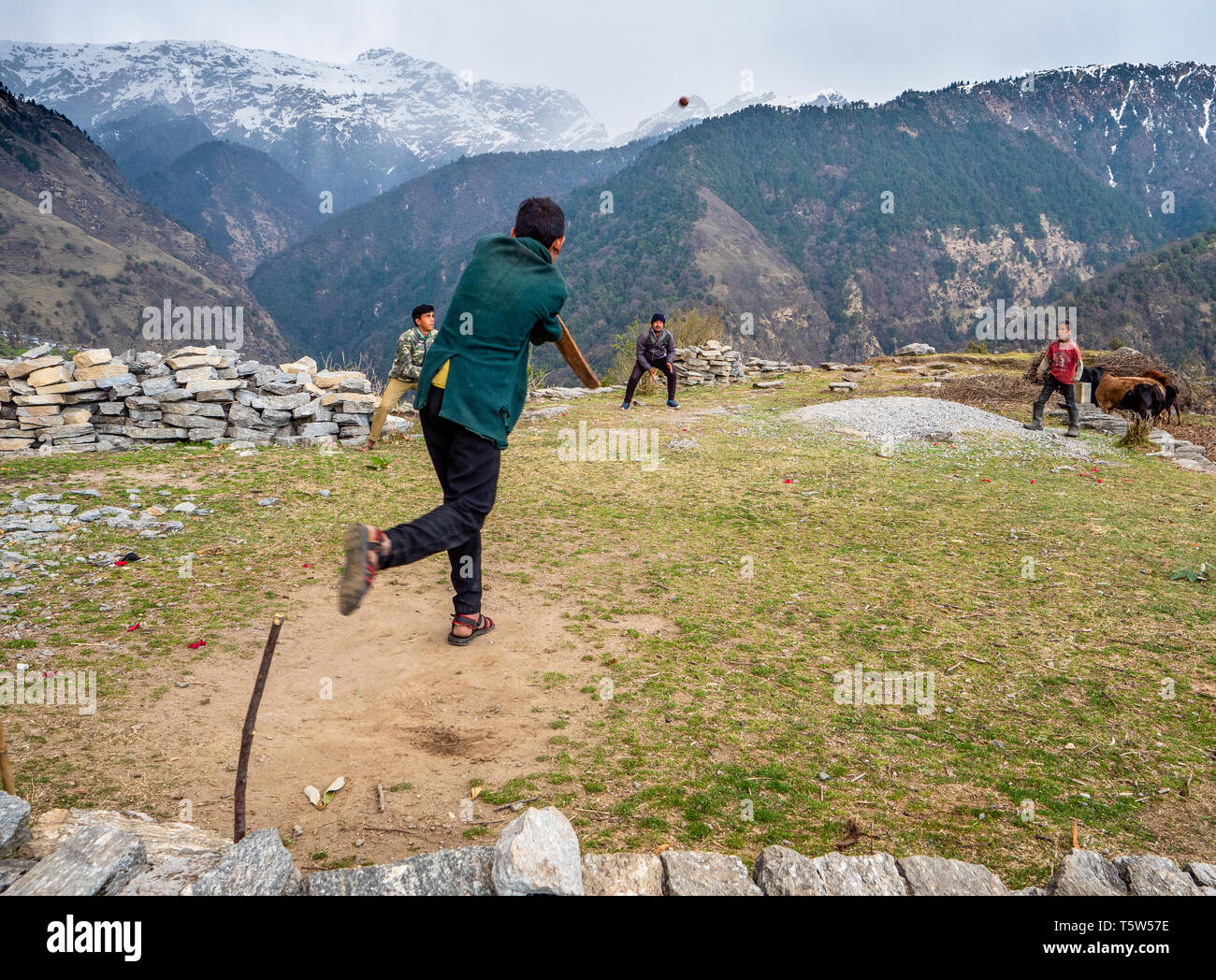 Young men playing cricket on a small makeshift pitch surrounded by steep slopes in Jhuni village in the Saryu Valley of Uttarakhand Himalayas India Stock Photo