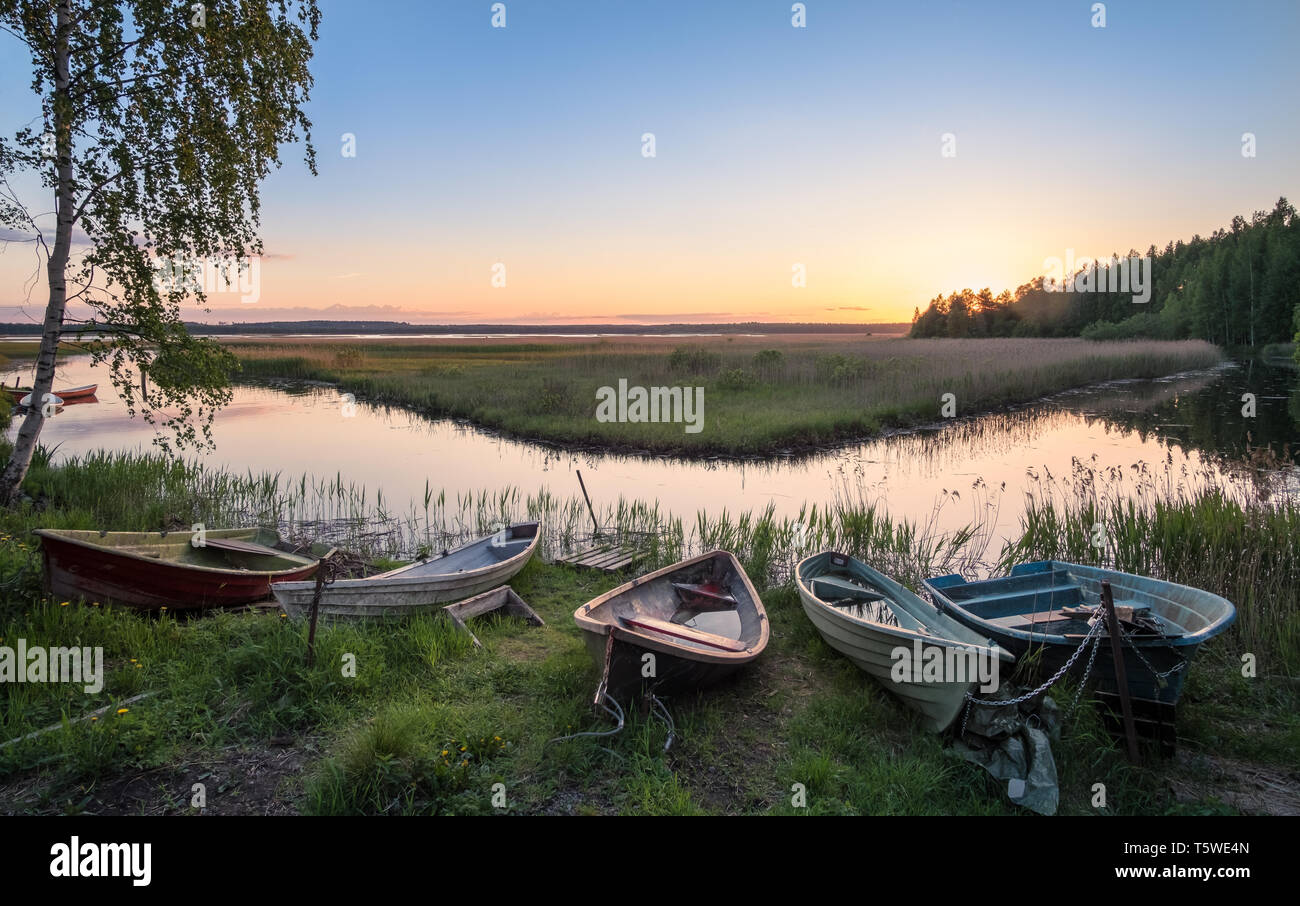 Beautiful sunset landscape with many row boats and peaceful lake at summer evening in Finland Stock Photo